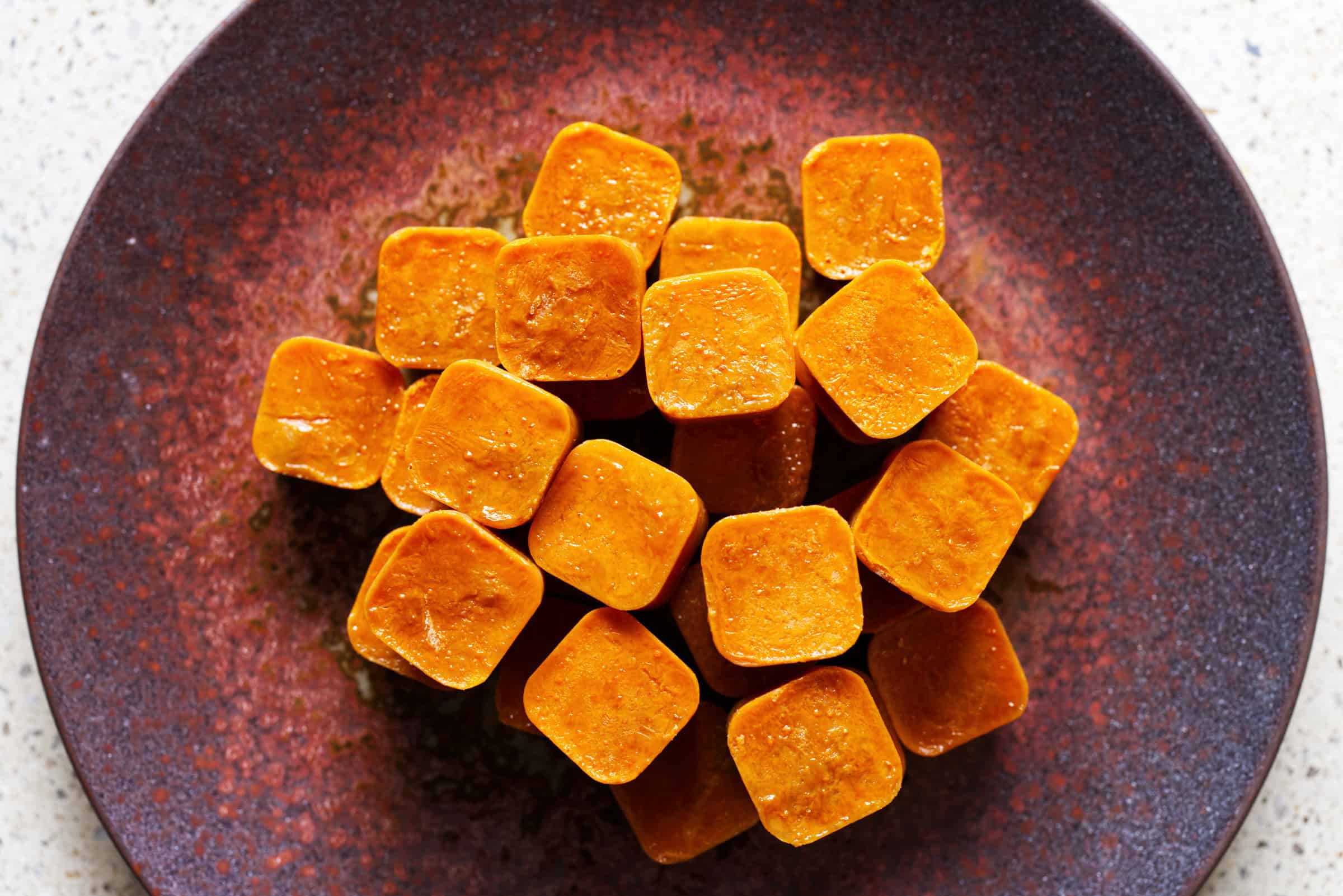 Homemade crustacean stock cubes arranged on a dark ceramic plate.