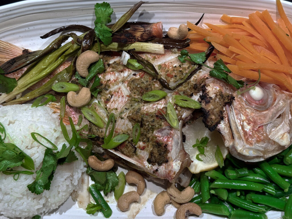 Whole grilled nannygai finished in Fan Grill, topped with a Thai-style herb and chilli paste, charred spring onions and cashews, served with jasmine rice, carrot, green beans and coriander